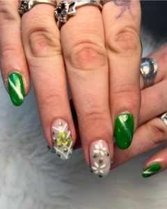 Image of St Patrick's Day themed nails featuring green and white patterns and clovers.
