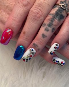 An image of red, white, and blue nails featuring red and blue chrome polish and rhinestones.