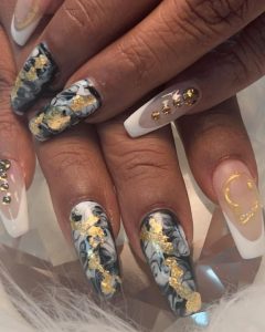 An image of marble-patterned nails with gold rhinestones.
