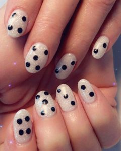 An image of white nails with black dots resembling a domino.